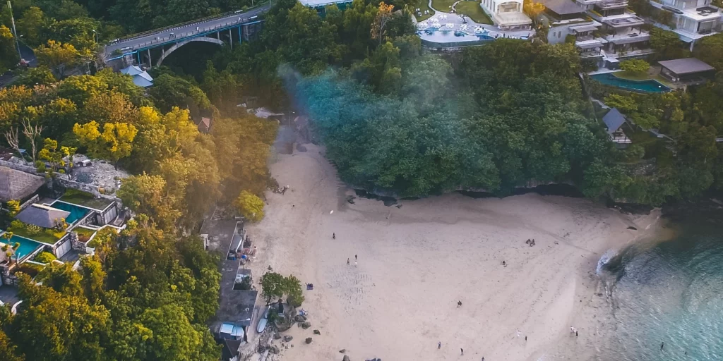 An image of Padang Padang Beach showing the ocean, sand, and walkway down from the cliff.