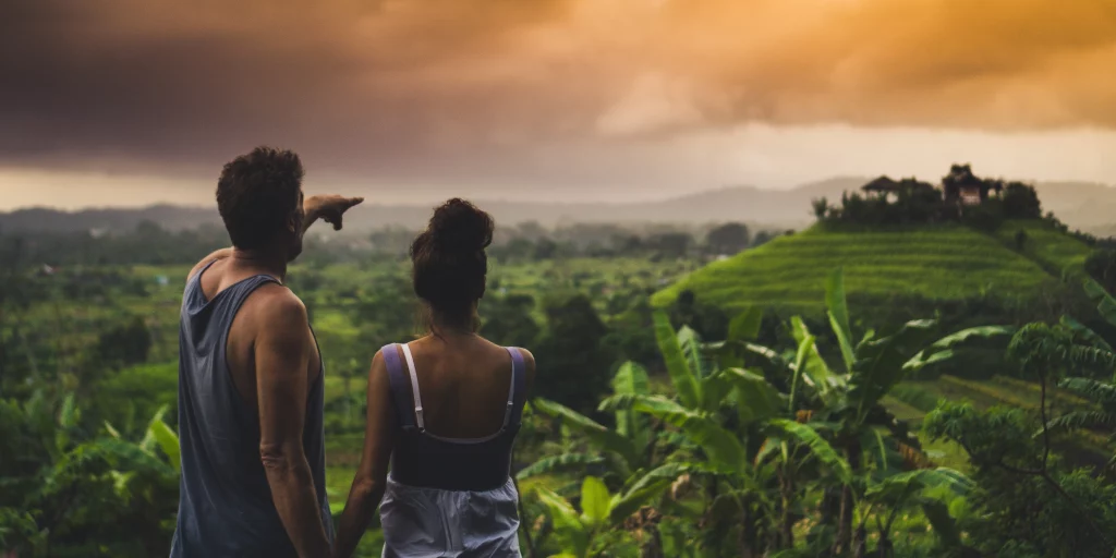 A couple in the foreground looking out over the Sidemen Rice Terraces stretching into the background.