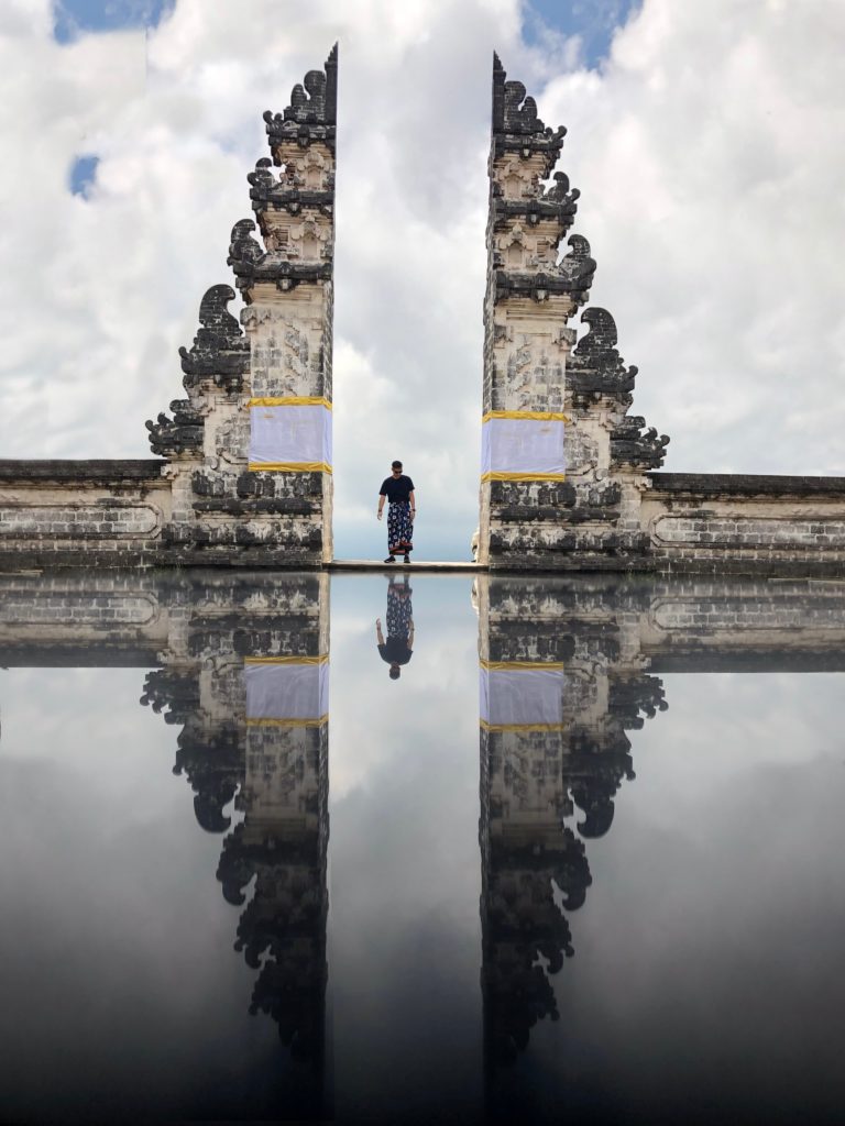 Man standing between the Gates of Heaven. A famous site within the Pura Lempuyang Luhur temple